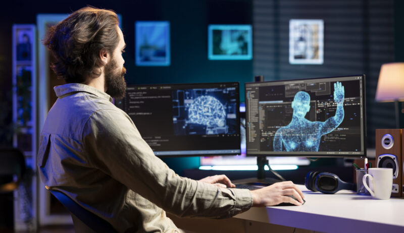 Self aware AI gaining humanoid form inside cyberspace, waving hand, saluting software engineer. Artificial intelligence becoming sentient, greeting IT expert at desk, AI singularity concept